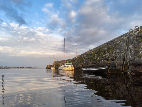 Small yachts and boat in Spiddal pier, county Galway, Ireland. Blue cloudy sky reflects in water. Warm sunny day. Nobody. photo