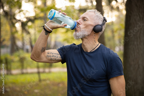 Sporty man drinking water during workout outdoors