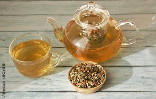 herbal tea in a glass teapot and a mug on a wooden table