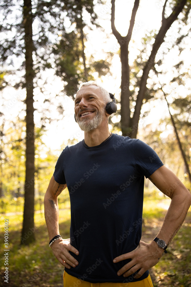 Obraz premium Happy fit man listening to music in wood