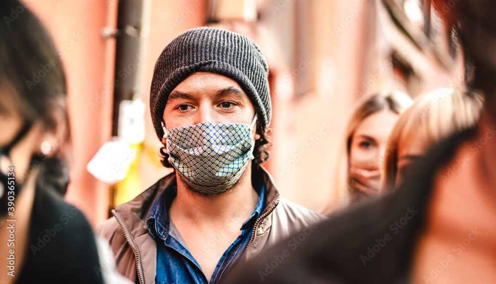 Urban crowd of citizens walking on city street wearing face mask - New normal reality lifestyle concept with people on worried alienated mood - Selective focus on man with hat - Warm contrast filter