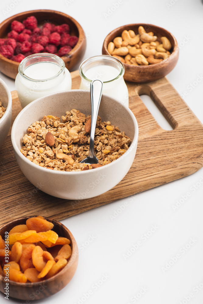 delicious granola with nuts, fruits and yogurt on wooden board on white background delicious granola with nuts, fruits and yogurt on wooden board on white background
