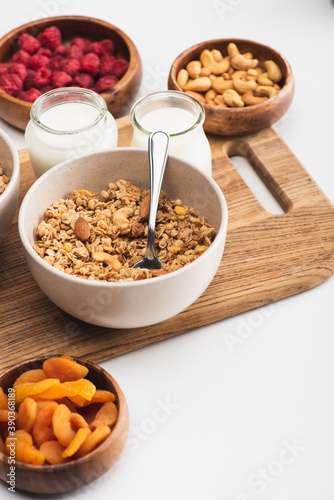 delicious granola with nuts, fruits and yogurt on wooden board on white background