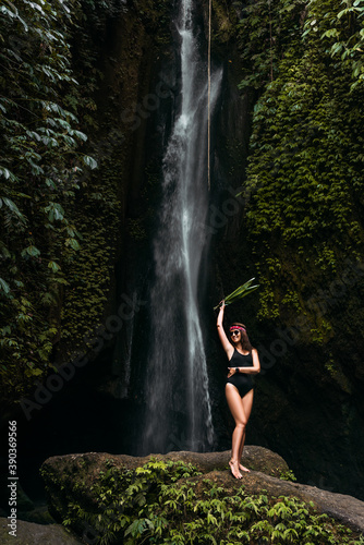 Beautiful girl at a waterfall on the island of Bali Indonesia. Sexy woman at the waterfall. Young and beautiful girl in bikini taking bath in a waterfall. Beautiful woman posing at a waterfall.