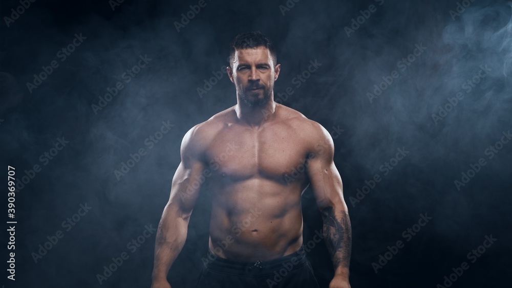 Obraz premium Fit and sporty bodybuilder over black background. Sportsman in studio. Sport and fitness concepts.