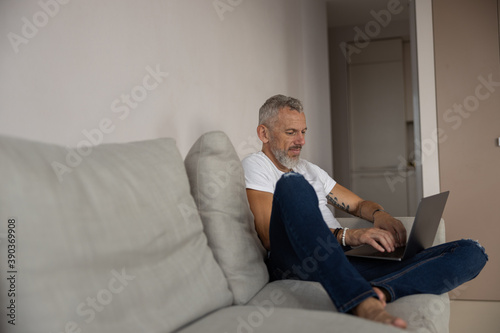 Concentrated man working on his laptop on a couch © Viacheslav Yakobchuk