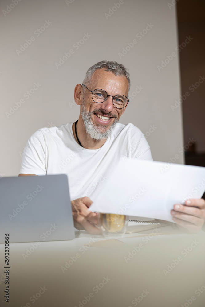 Cheerful entrepreneur raising a piece of paper to his eyes