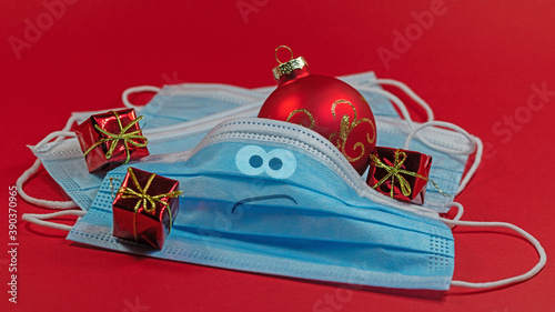 Mundschutzmasken mit Weihnachtsdekoration vor rotem Hintergrund
