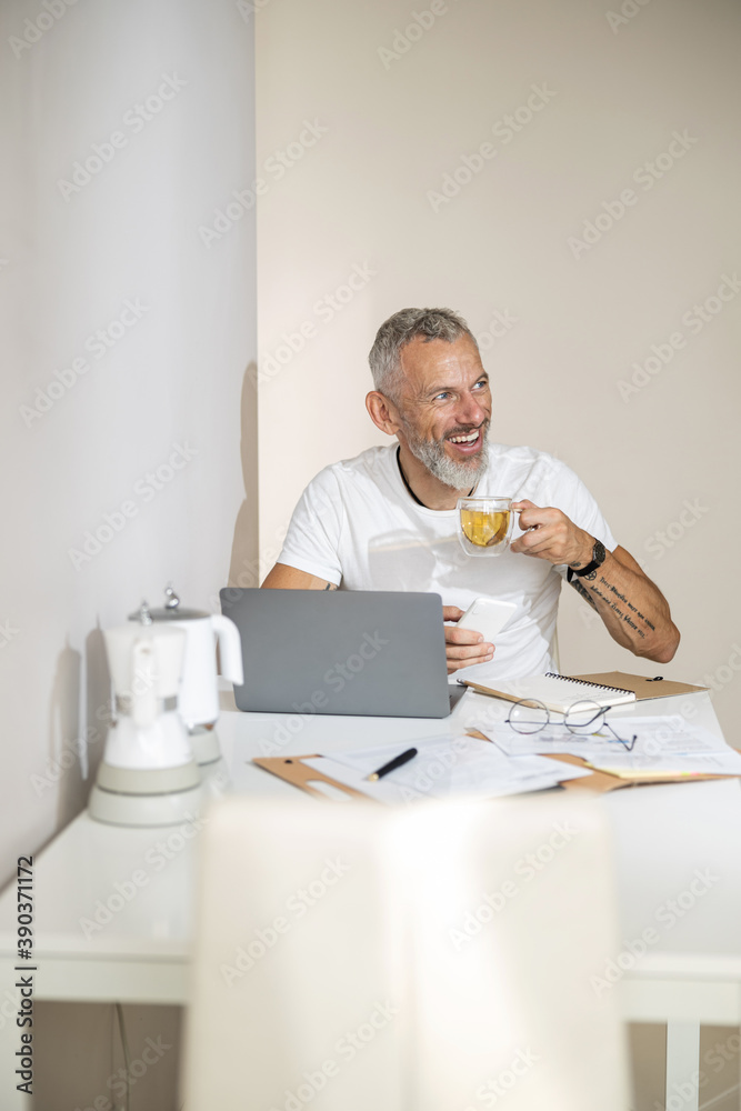 Adult enjoying his tea while working at the laptop Adult enjoying his tea while working at the laptop