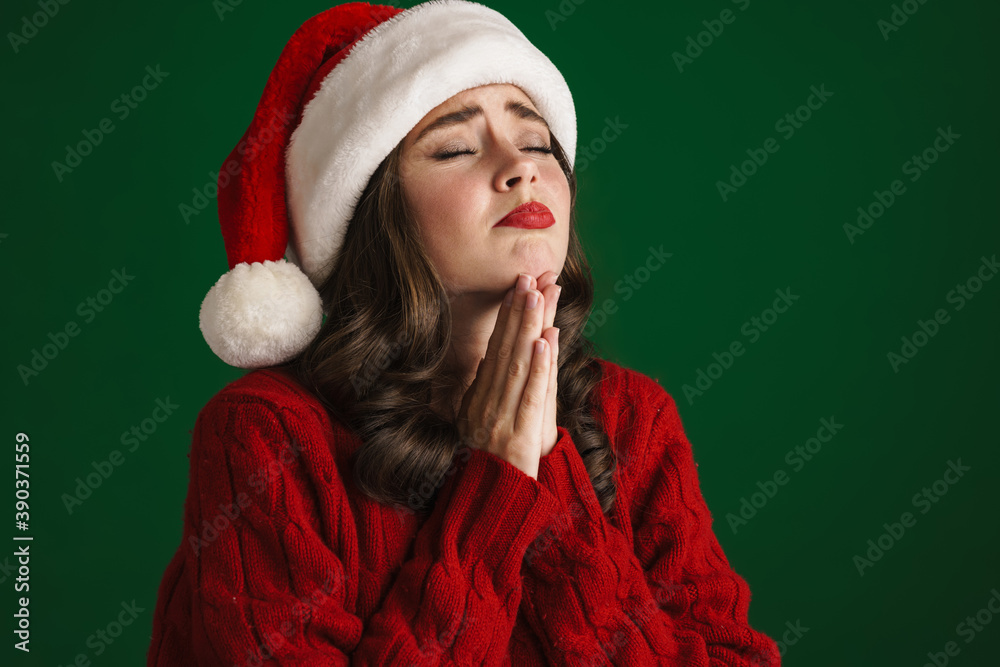 Nice tense girl in Santa Claus hat posing with palms together Nice tense girl in Santa Claus hat posing with palms together