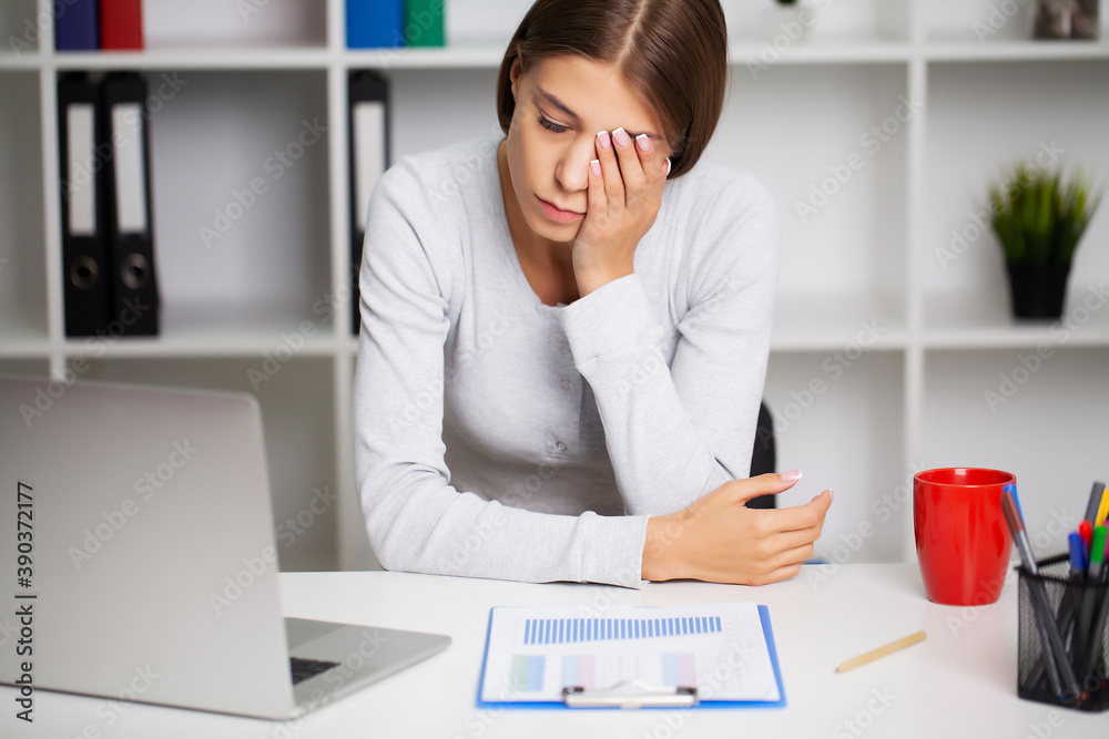 Woman working at office desk in front of laptop suffering from chronic daily headaches. Woman working at office desk in front of laptop suffering from chronic daily headaches.