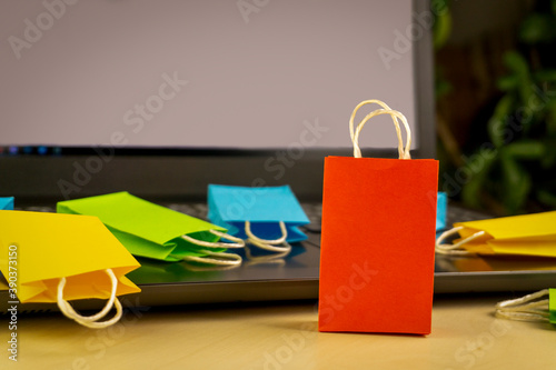 online shopping concept. little deliver boxes, smartphone, shopping bags, shopping bascket stand on laptop. copy space