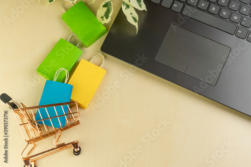 online shopping concept. little deliver boxes, smartphone, shopping bags, shopping bascket stand on laptop. copy space
