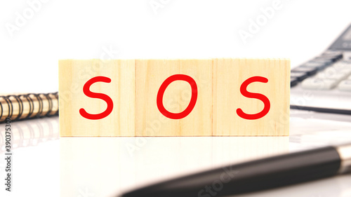 A wooden block with the word sos written on it on a white background. Business concept