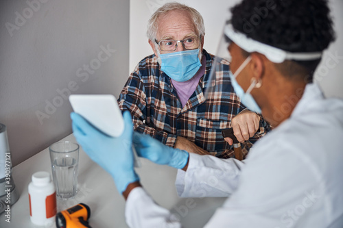 Pensioner looking at the geriatrician with a portable computer photo