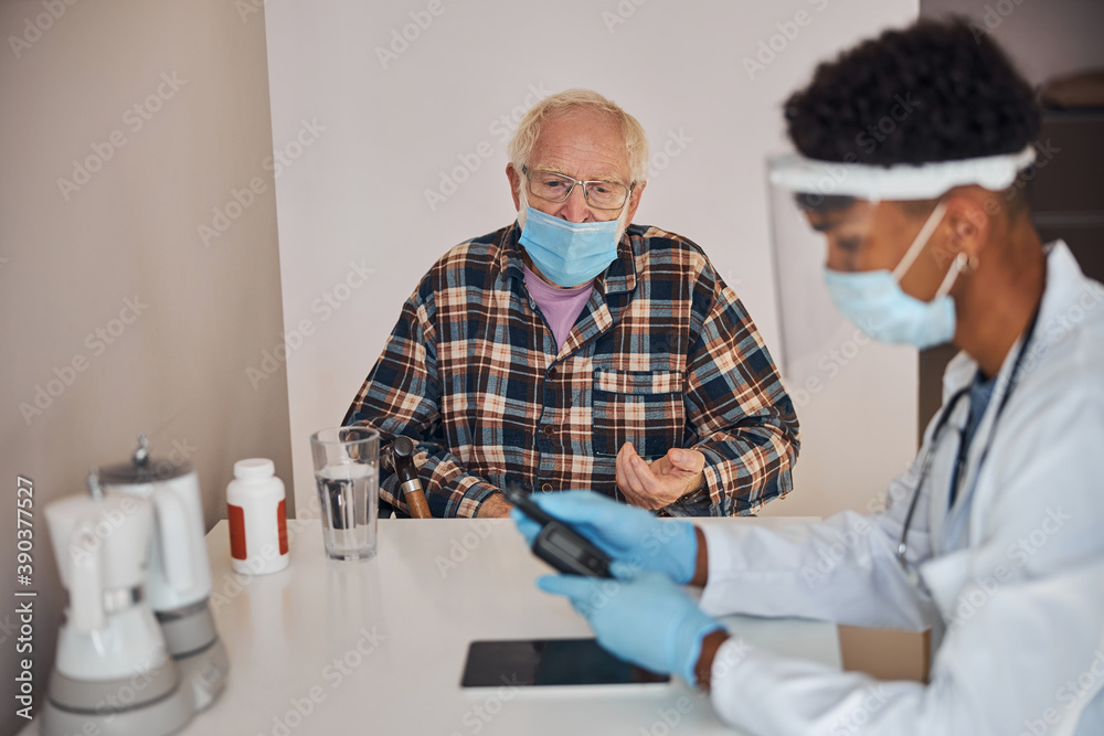 Senior patient staring at the doctor with a glucose meter
