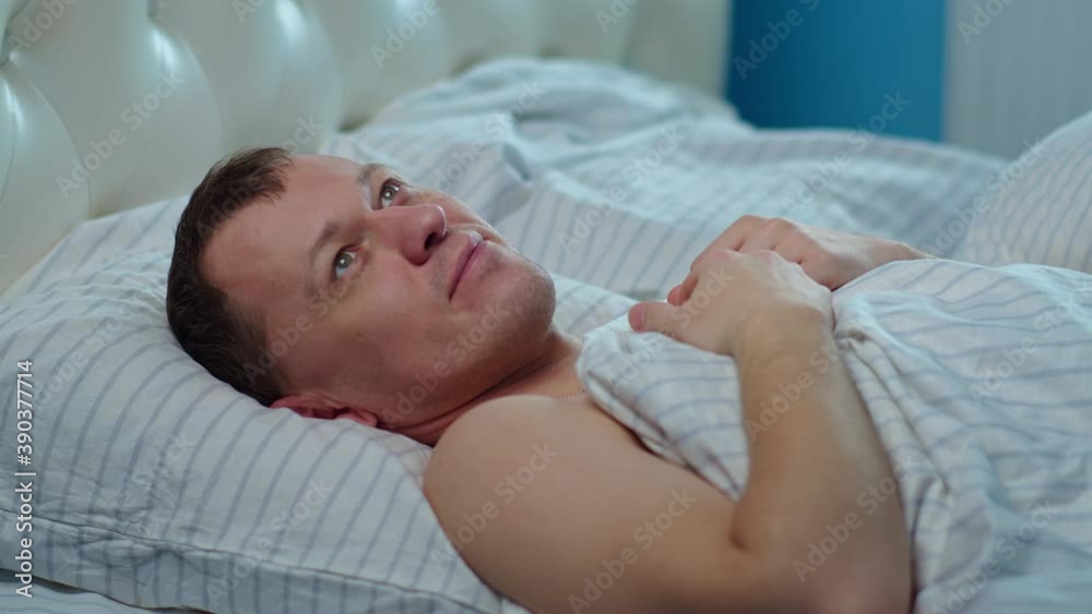 Young man dreaming while lying in bed before going to bed, camera movement Young man dreaming while lying in bed before going to bed, camera movement