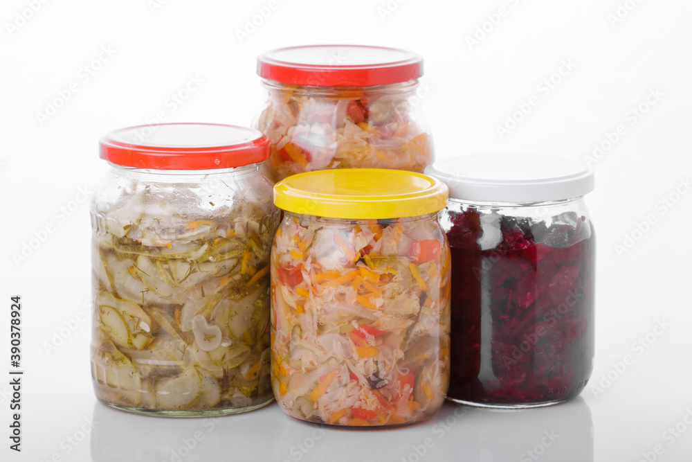 Glass jars of pickled homemade organic cucumber carrrot with garlic and red cabbage vegetables isolated on white background Glass jars of pickled homemade organic cucumber carrrot with garlic and red cabbage vegetables isolated on white background