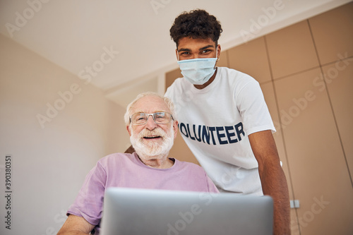 Happy pensioner with a laptop and his caretaker