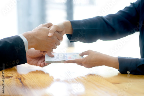 Businessman shake hand with officer and hold the cash