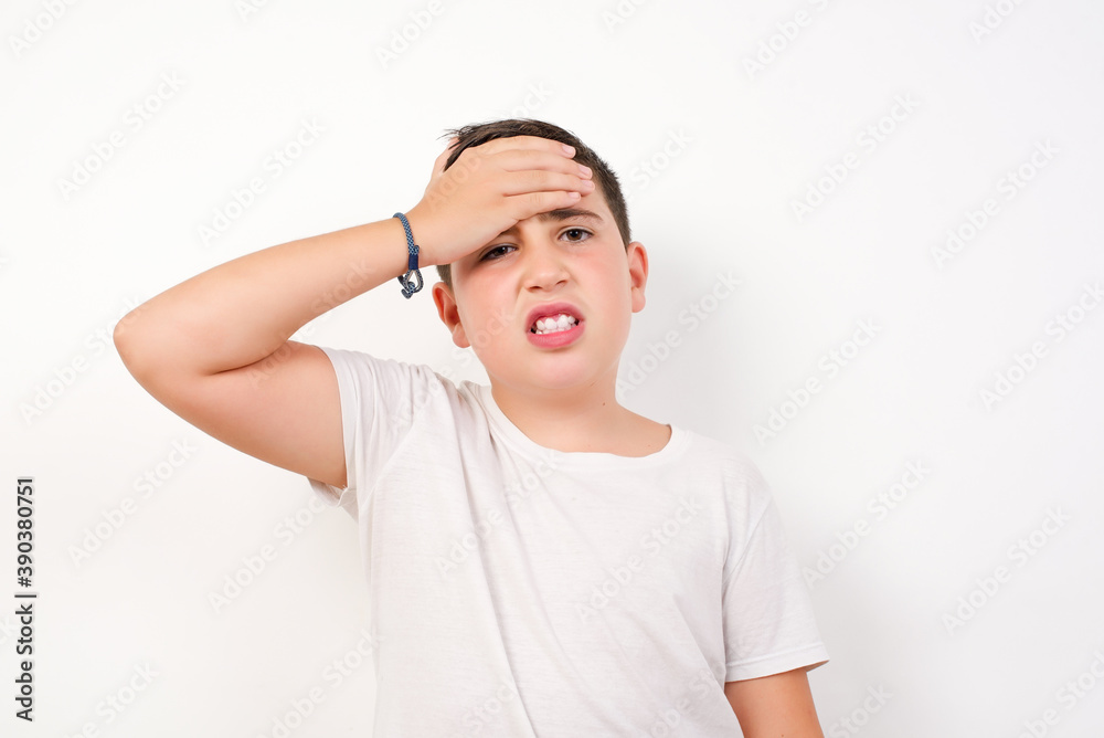 Oops, what did I do? Caucasian young boy standing against white background holding hand on forehead with frightened and regret expression. Oops, what did I do? Caucasian young boy standing against white background holding hand on forehead with frightened and regret expression.