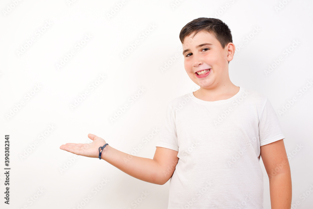 Positive glad Caucasian young boy standing against white background says: wow how exciting it is, has amazed expression, shows something on blank space with open hand. Advertisement concept. Positive glad Caucasian young boy standing against white background says: wow how exciting it is, has amazed expression, shows something on blank space with open hand. Advertisement concept.