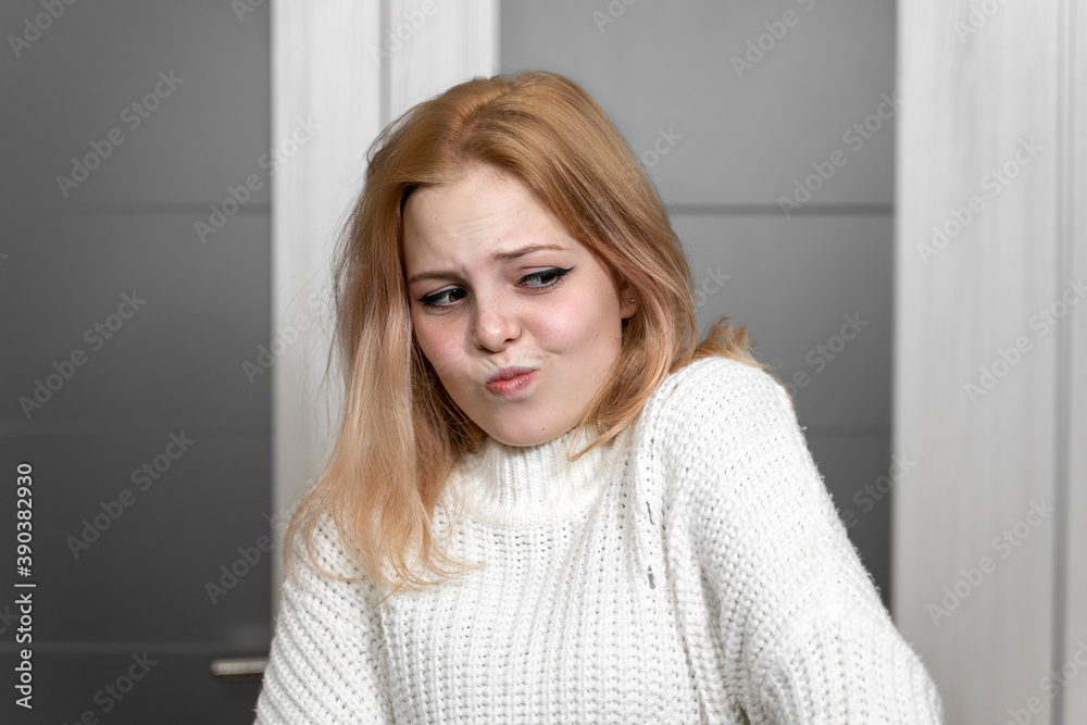 girl teenager in a white sweater expresses disdain, grimacing. Human emotions. Facial expression concept. girl teenager in a white sweater expresses disdain, grimacing. Human emotions. Facial expression concept.