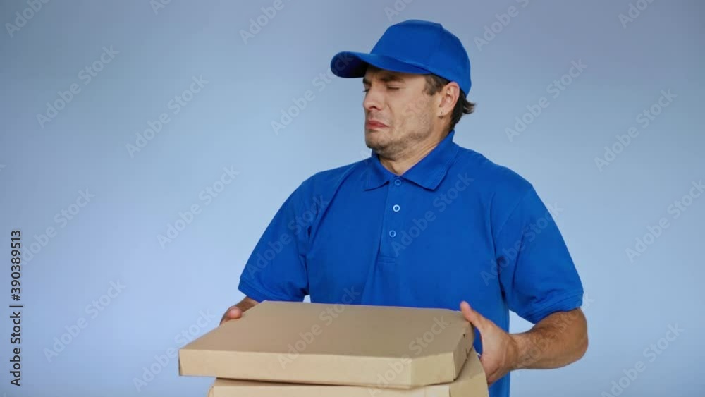 displeased delivery man holding smelly pizza in boxes on grey displeased delivery man holding smelly pizza in boxes on grey