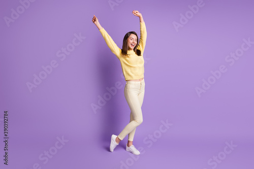 Photo portrait of young girl dancing with hands in air laughing isolated on vivid purple colored background