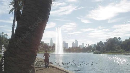 Single Man Goes Fishing Standing Up at Echo Park Lake, with Downtown LA City in Background photo