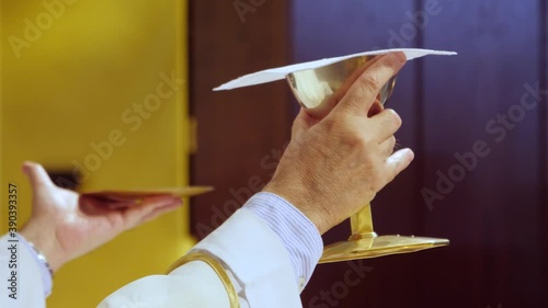 hand of a priest raising the holy chalice that represents the blood of christ and the sacred form that represents the body of christ during the office of holy mass photo