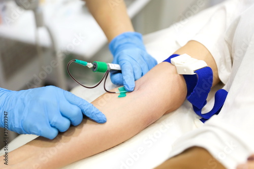 taking blood from a vein close-up. blood test in the hospital. the doctor s hands draw blood from a vein. blood sampling for plasma extraction