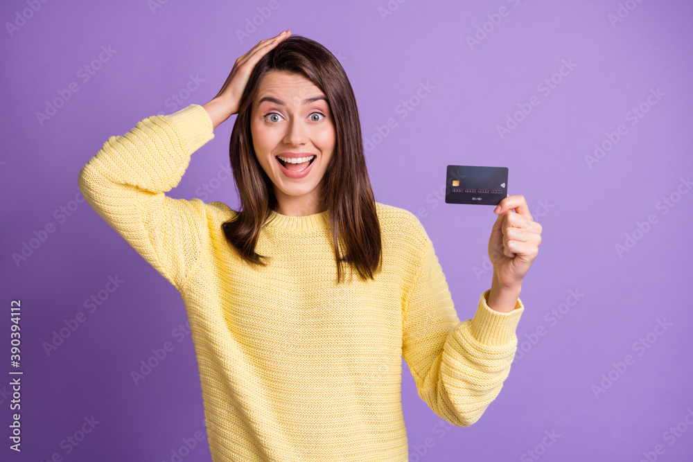 Photo portrait of woman holding plastic card touching head hair with open mouth isolated on vivid purple colored background