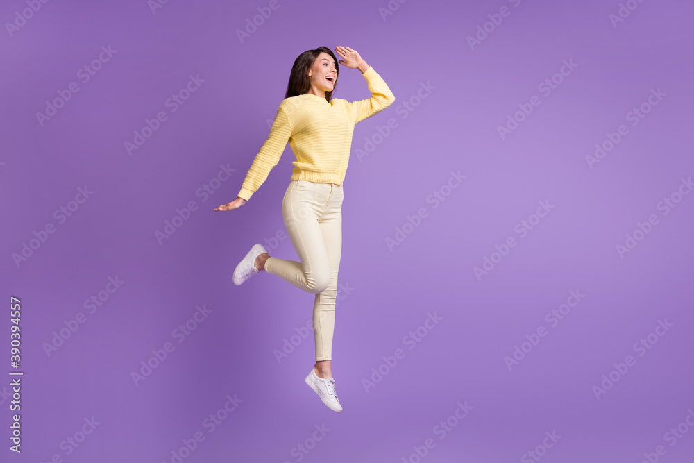 Full length photo portrait of girl looking in distance with head near forehead jumping up isolated on vivid violet colored background