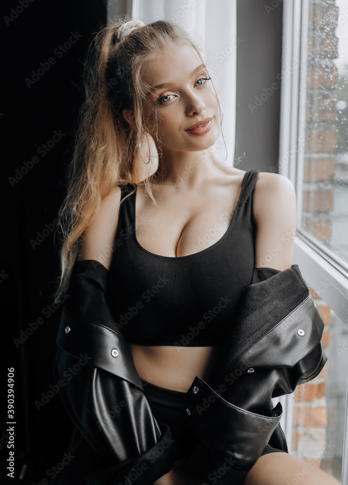 Comely blonde in fashionable black clothes posing near the window. Comely blonde in fashionable black clothes posing near the window.