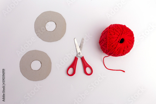 making red pompons from thread, top view, white background, handmade craft, DIY, instruction step 1