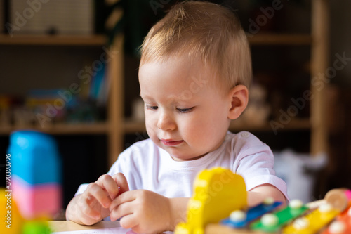 Cute little girl playing alone with many colorful toys