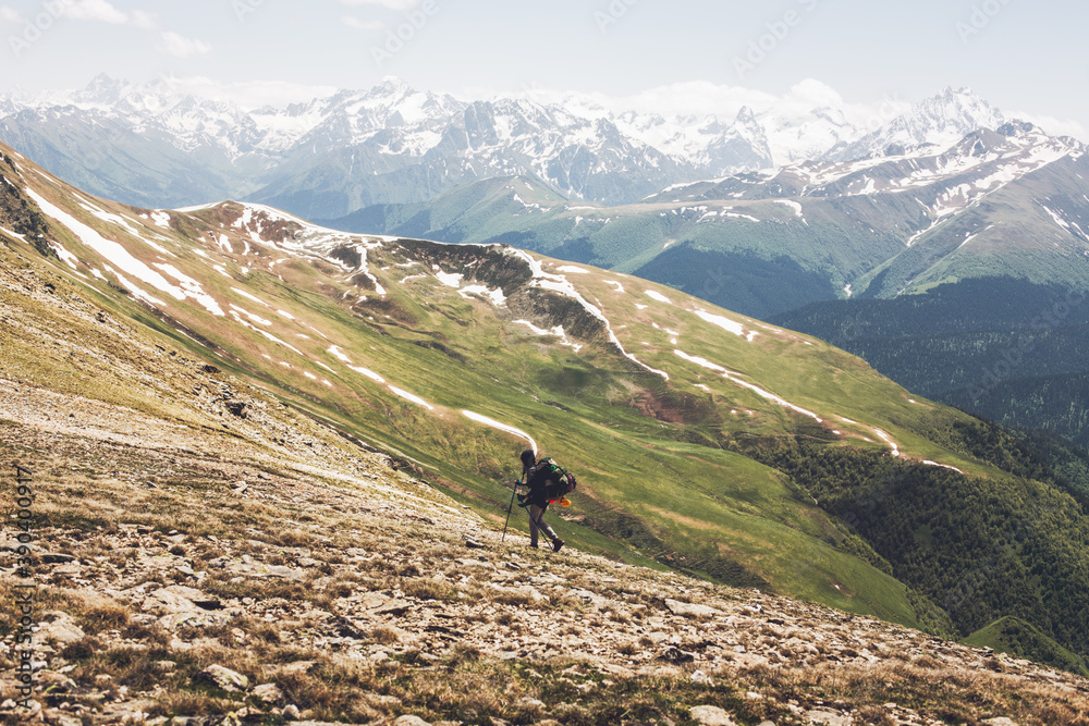 Climber traveler with a heavy backpack climbs to the top of the mountain
