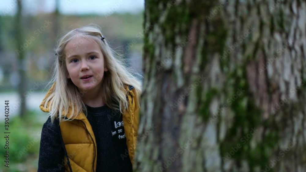 Portrait of a cute little girl. funny girl looks out from behind a tree. playing hide and seek with mom. close up Shot video. Slow motion footage Portrait of a cute little girl. funny girl looks out from behind a tree. playing hide and seek with mom. close up Shot video. Slow motion footage