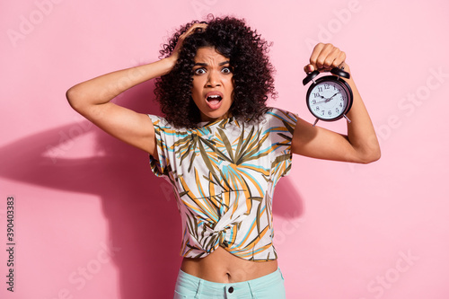 Portrait photo of clueless troubled curly african woman showing watch late grimacing isolated on pastel pink color background