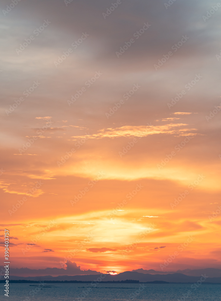 Dusk sky vertical in the evening over sea and sundown behind islands silhouette with colorful sunlight clouds