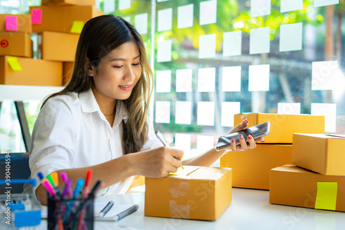 Starting small businesses SME owners female entrepreneurs Write the address on receipt box and check online orders to prepare to pack the boxes, sell to customers, sme business ideas online. © crizzystudio