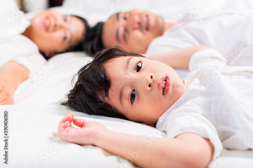 Friendly family. Asian family in white shirt are sharing good emotions while relaxing in bed together at home