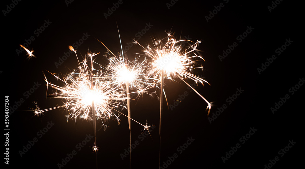 Three burning sparklers on a black background with place for text