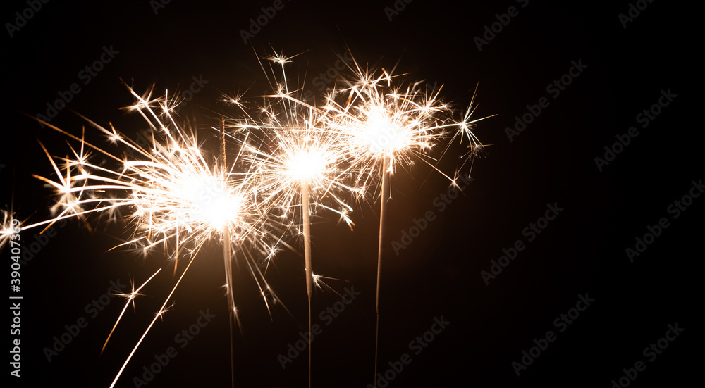 Three burning sparklers on a black background with place for text