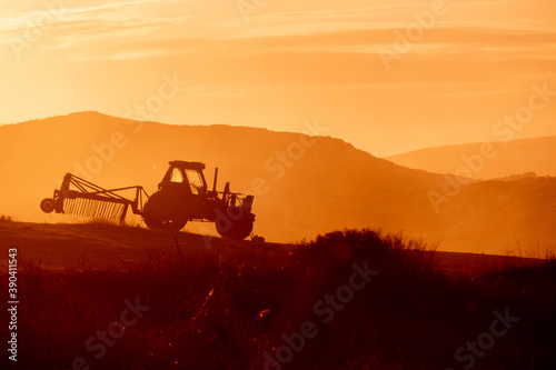 Tractor in a farm field at sunset. Backlight warm tones. © Rojo