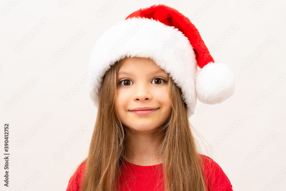 A little girl posing on a white background in a Christmas hat. A little girl posing on a white background in a Christmas hat.