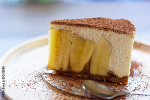 Close up Banoffee pie cake with chocolate powder on wooden plate. Homemade banoffee pie mix with Crushed crackers, banana, freah whipping cream, chocolate powder. photo