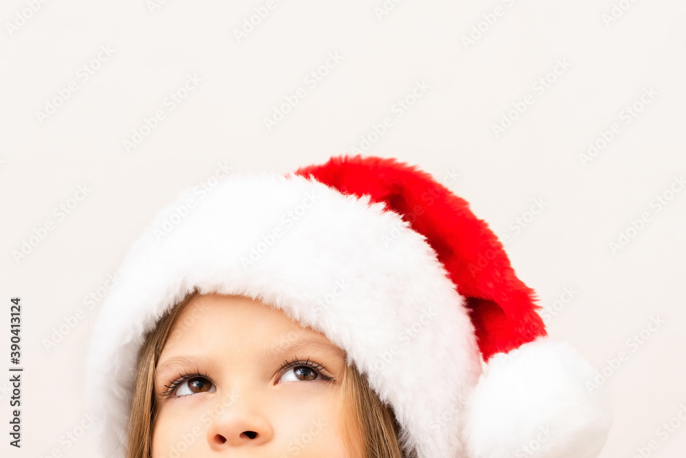 A cute little girl in a red Christmas hat looks up. A cute little girl in a red Christmas hat looks up.