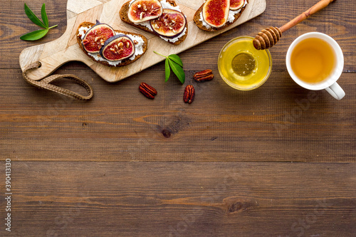 Fototapeta Naklejka Na Ścianę i Meble -  Toasted bread with figs, ricotta and honey on wooden cutting board